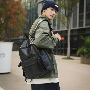 Photo en extérieur d'un homme portant un sac à dos noir en similicuir et veste verte