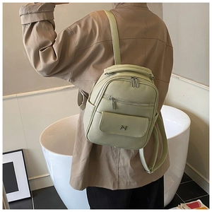 Detail view of pistachio green lychee pattern leather backpack with metal logo and pockets