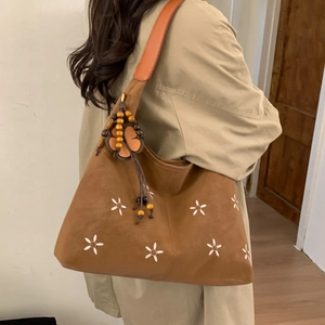 Détail du sac cabas en simili daim marron avec broderie florale et breloque bohème