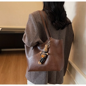Detail view of large brown faux leather tote bag with a cute plush rabbit pendant charm