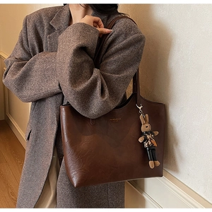 Detail of dark brown tote bag in oil wax leather with bunny charm and printed text