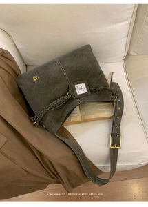 Detail of vintage olive green bucket bag with gold logo on a white soft sofa