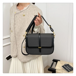 Close-up of minimalist black rectangle crossbody bag with gold buckle and textured leather