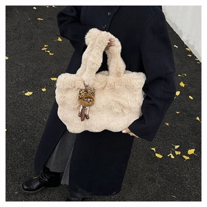 Détail d'un sac cabas en peluche beige avec breloque léopard sur fond de rue d'automne