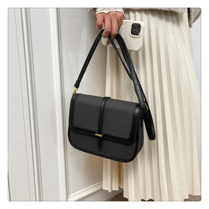 Detail of minimalist fabric square bag with black leather trim and golden metal clasp