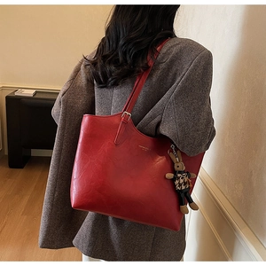 Detail of red leather tote bag with a leopard print bunny charm on a brown blazer
