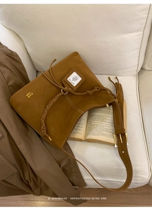 Detail view of brown suede bucket bag featuring drawstring closure and woven shoulder strap