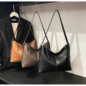 Detailed view of three faux leather tote bags in caramel, brown, and black colors