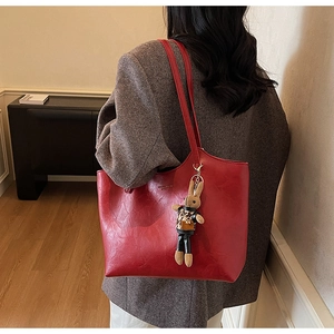Detail of deep red tote bag with a small rabbit doll charm in leopard print jacket