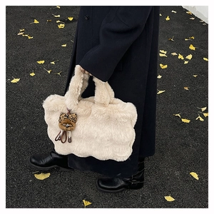 Détail d'un sac cabas beige en fausse fourrure avec charm léopard dans un décor d'automne