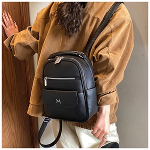 Close-up detail of black litchi pattern leather backpack with silver metal zippers