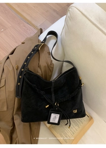 Macro shot of black suede hobo bag with gold PAN TOR logo and contrast white stitching