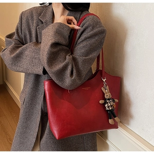 Detail of red oversized tote bag with gold logo lettering and a cute bunny bag charm