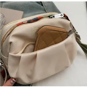 Detail of cream nylon crossbody bag showing multiple pockets and spacious interior storage
