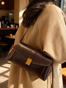 Vintage dark brown leather crossbody bag with white stitching and gold buckle