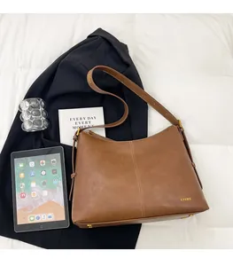 Detail of a brown leather tote bag showing vertical stitching and gold brand logo