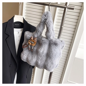 Détail du sac fourre-tout en fausse fourrure grise avec charm oiseau et nœud léopard