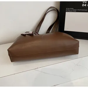 Detail view of brown tote bag with decorative patterned scarf handle and leather texture