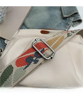 Detail of off-white nylon crossbody bag featuring a colorful floral jacquard woven wide strap