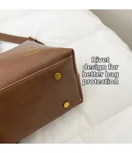 Detail view of brown leather tote bag featuring protective gold-tone base studs