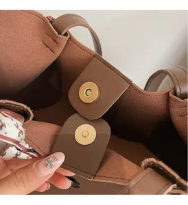 Detail of brown leather tote with gold magnetic closure and printed silk ribbon