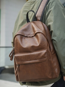 Sac à dos marron vintage en similicuir porté par un mannequin en manteau vert foncé