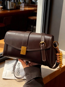 Retro dark brown crossbody bag with gold hardware and beaded charm in a cafe setting