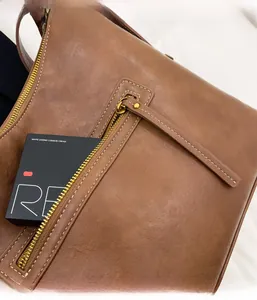 Detail of the back zipper pocket on a brown vintage leather tote bag with a long puller