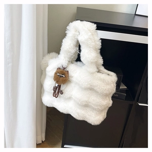 Détail d'un sac cabas en fausse fourrure blanche avec un pendentif peluche marron mignon