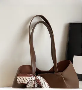 Close-up of brown leather tote bag with printed silk scarf and durable shoulder straps