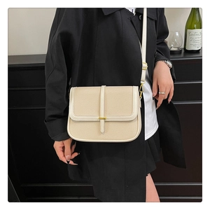 Detail of cream woven crossbody bag with leather trim and gold buckle worn by a model