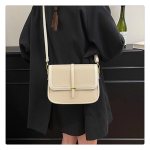 Detail of a beige canvas crossbody square bag with golden hardware on a model