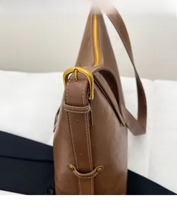 Detail of vintage brown leather tote featuring bronze buckle and contrast stitching