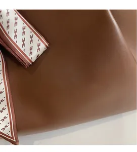 Detail of soft brown leather tote with decorative geometric pattern silk scarf