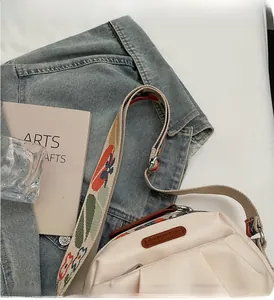 Close-up of beige canvas shoulder bag with colorful woven strap and brown leather patch