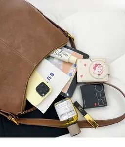 Flat lay showing large capacity interior of brown leather tote bag with various accessories