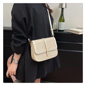 Detail of retro crossbody bag with beige texture and gold metallic clasp on a model