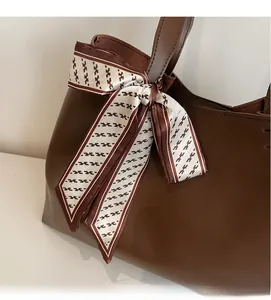 Detail of dark brown leather tote bag decorated with a patterned silk scarf on the handle