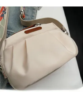 Detail of off-white pleated nylon bag with jacquard strap and leather logo patch