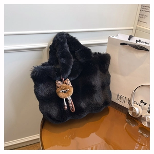 Gros plan d'un sac cabas en peluche noire avec breloque d'ours en peluche et nœud léopard