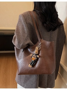Brown leather tote bag with fashion print and rabbit charm shown on shoulder