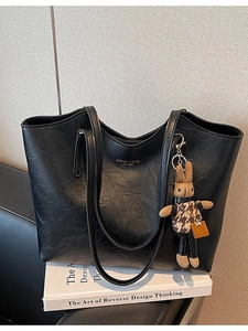 Black pebbled leather tote bag with long straps and a cute brown plush rabbit charm