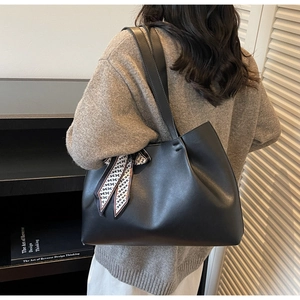 Detail of black leather tote bag featuring a decorative black and white patterned silk scarf