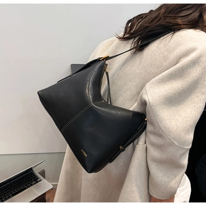 Detail of black leather hobo bag with contrast stitching and adjustable wide strap