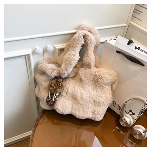 Détail d'un sac cabas en fausse fourrure beige avec un charm d'ours sur une table