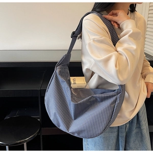 Dettaglio borsa blu a scacchi con tracolla regolabile e design a mezza luna moderno