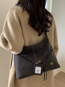 Retro dark brown large bucket bag with woven rope detail on model in camel coat