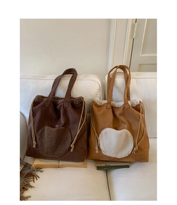 Close-up of fluffy faux shearling heart detail on large suede tote bags in brown and khaki