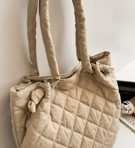 Détail du sac à bandoulière matelassé beige montrant la texture douce et la poignée nouée