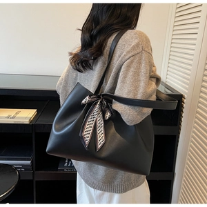 Detail of black tote bag with decorative patterned scarf and slim shoulder strap